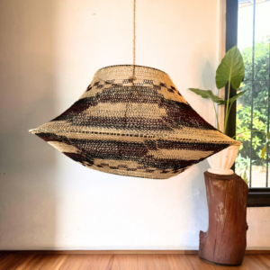 Handcrafted pendant lamp made from natural caraguatá fiber, handwoven by artisans in Paraguay. Its elongated and lightweight shape (80 cm diameter x 30 cm height) allows light to gently pass through the woven structure, creating a warm, organic and atmospheric illumination.
